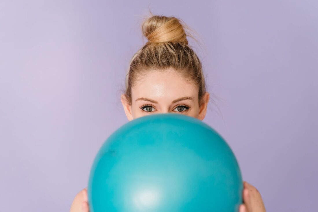 happy gymnast showing blue ball in hands