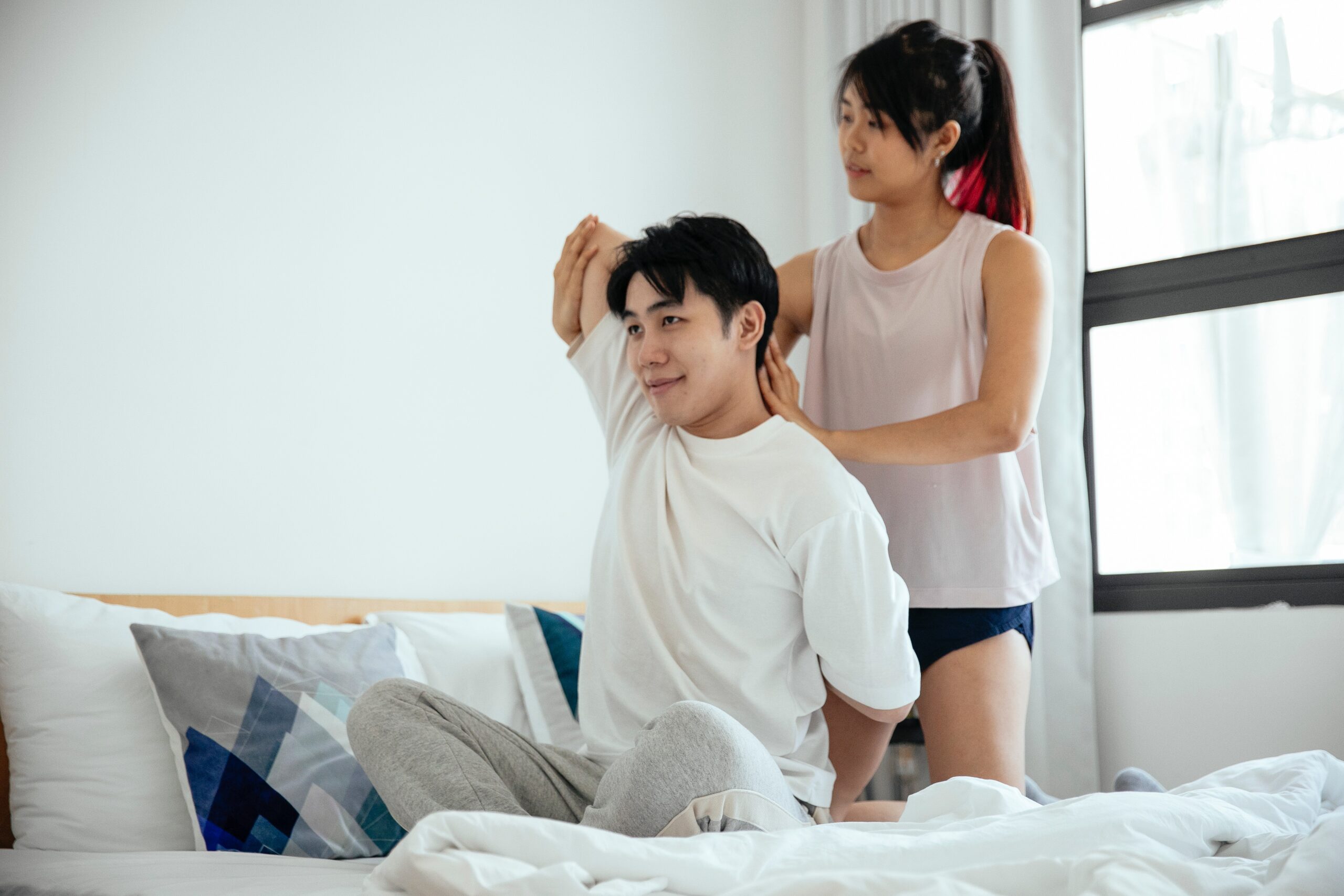 Young woman helping a partner with bedtime workout challenge stretching for fitness